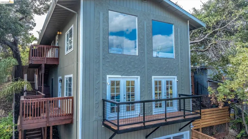 Multi-level exterior with a modern balcony, a wood-finish deck, and large windows
