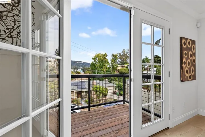 Sliding glass French doors opening to a wood-plank balcony with a metal railing