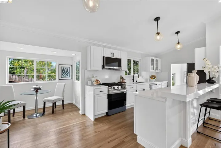 Kitchen featuring white cabinetry, light-toned wood-finish flooring, recessed lighting, and a breakfast bar with a solid surface countertop
