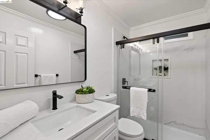 White vanity with an integrated rectangular sink, matte black faucet, and a framed mirror