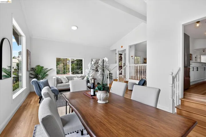Vaulted ceilings, wood-finish flooring, white walls, multiple windows, and white balustrade