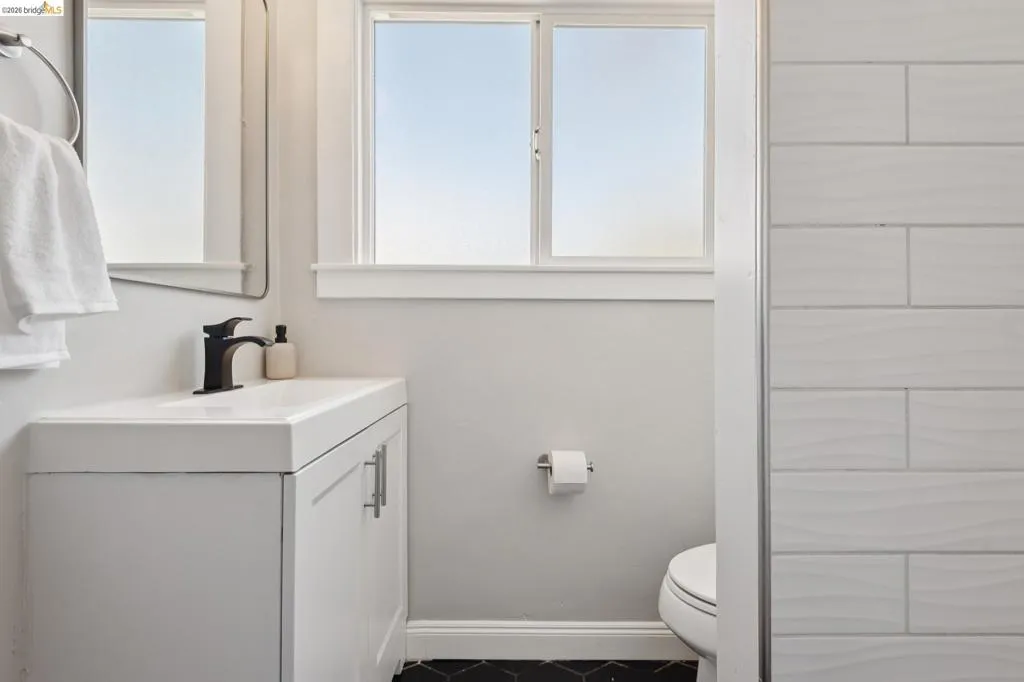 White vanity with integrated sink, matte black faucet, and black hexagonal tile flooring White vanity with integrated sink, matte black faucet, and black hexagonal tile flooring