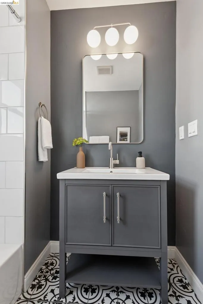 Single vanity with a white countertop and integrated sink, chrome faucet, and gray cabinetry Single vanity with a white countertop and integrated sink, chrome faucet, and gray cabinetry