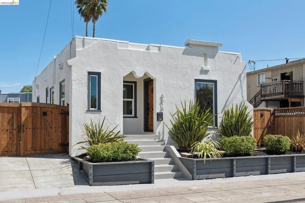 Stucco exterior with dark trim windows, concrete steps, and integrated planter boxes with established landscaping Stucco exterior with dark trim windows, concrete steps, and integrated planter boxes with established landscaping
