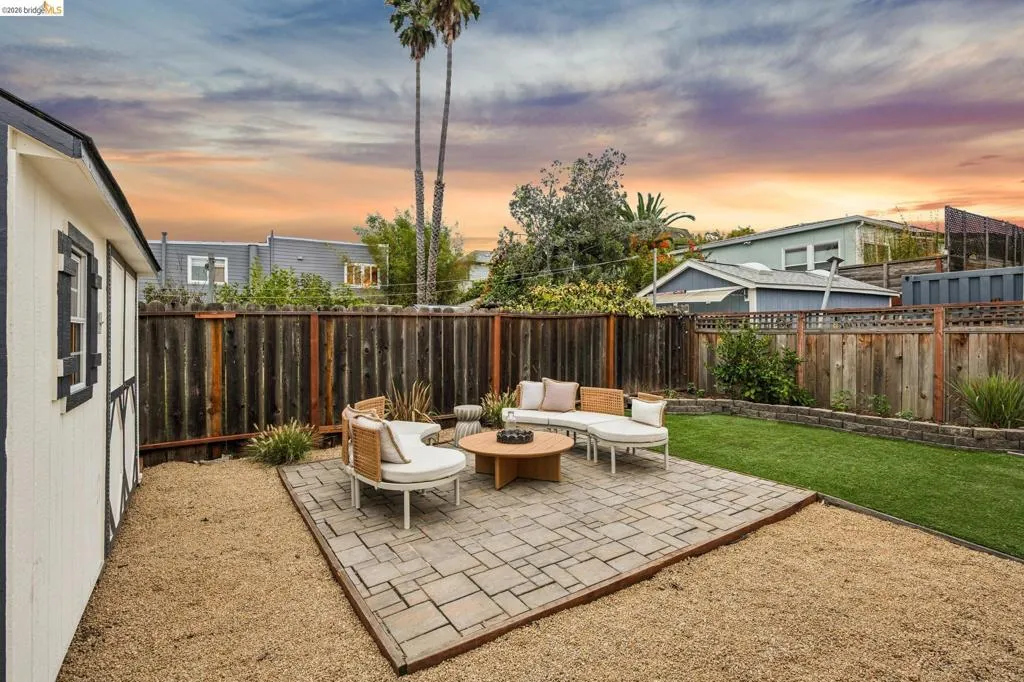 Expansive outdoor space featuring a paved patio, gravel ground cover, and a strip of artificial turf Expansive outdoor space featuring a paved patio, gravel ground cover, and a strip of artificial turf