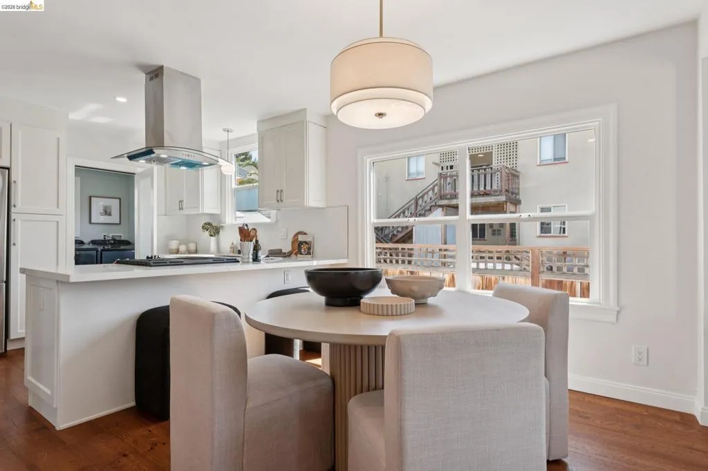 Kitchen featuring white cabinetry, stainless steel range hood, integrated cooktop, and a large window with white trim Kitchen featuring white cabinetry, stainless steel range hood, integrated cooktop, and a large window with white trim