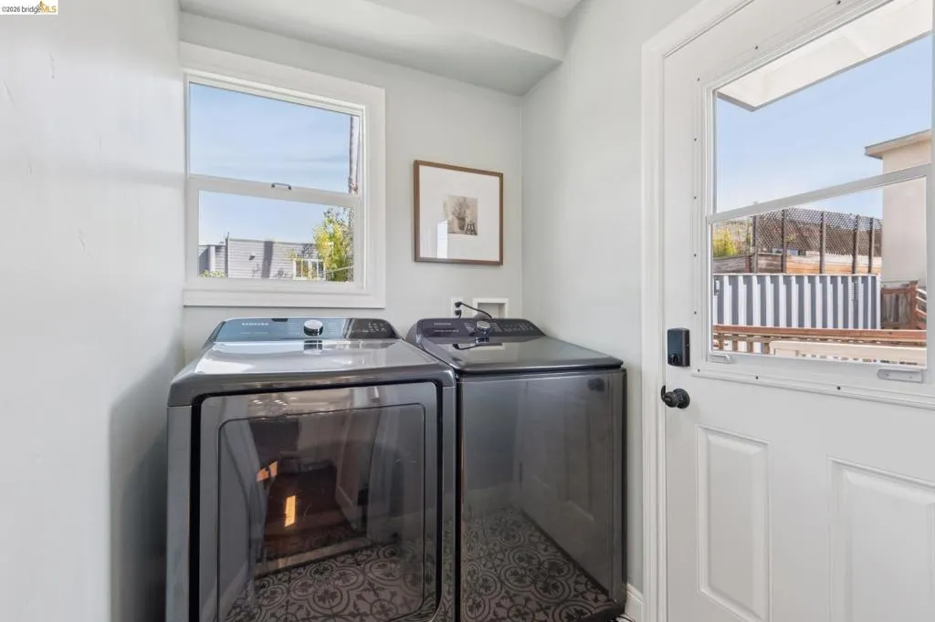 Laundry area featuring a window, patterned floor tile, and a door with a windowpane Laundry area featuring a window, patterned floor tile, and a door with a windowpane