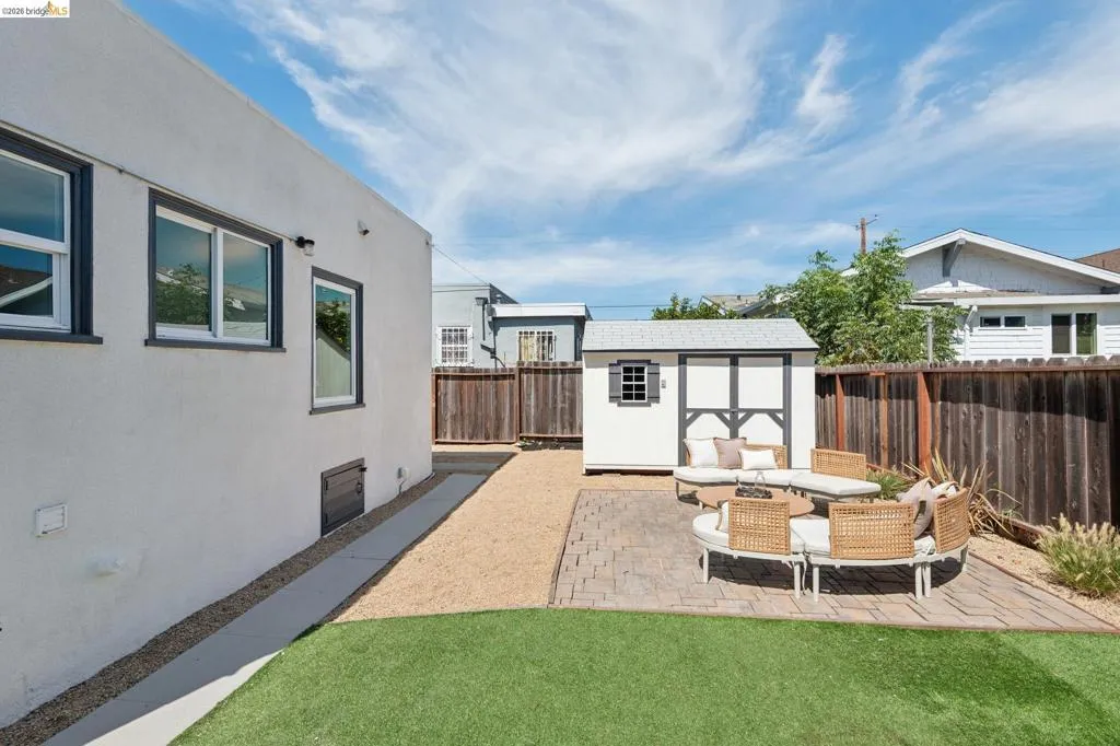 Manicured lawn with a brick paver patio, gravel hardscaping, and a backyard shed with shingled roof Manicured lawn with a brick paver patio, gravel hardscaping, and a backyard shed with shingled roof