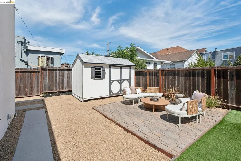 Spacious backyard featuring a paver patio, artificial turf, gravel landscaping, and a storage shed Spacious backyard featuring a paver patio, artificial turf, gravel landscaping, and a storage shed