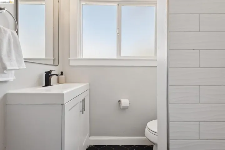 White vanity with integrated sink, matte black faucet, and black hexagonal tile flooring