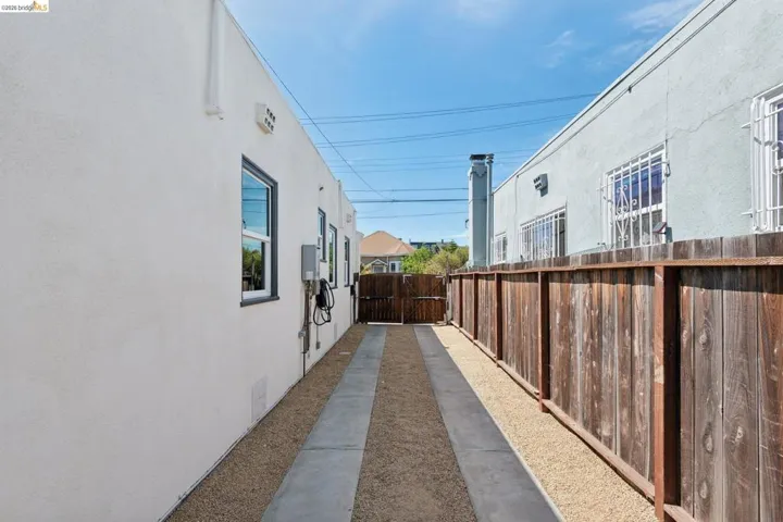 Gravel driveway with concrete tire tracks, wooden privacy fence, and rear gate access