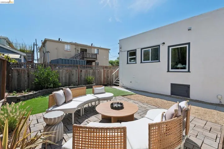 Paver patio with a gravel border, artificial turf landscaping, and a wood privacy fence