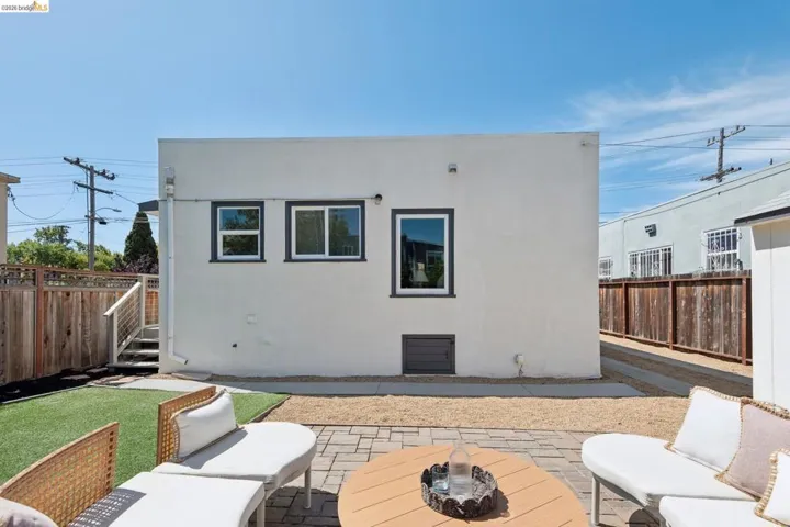 Private patio area featuring a paver stone surface, artificial turf, and gravel landscaping