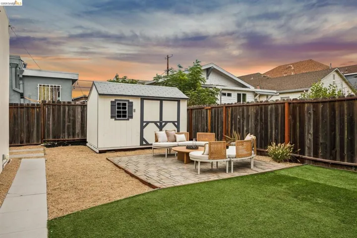 Backyard featuring artificial turf, a paved patio area, a detached storage shed, and a privacy fence
