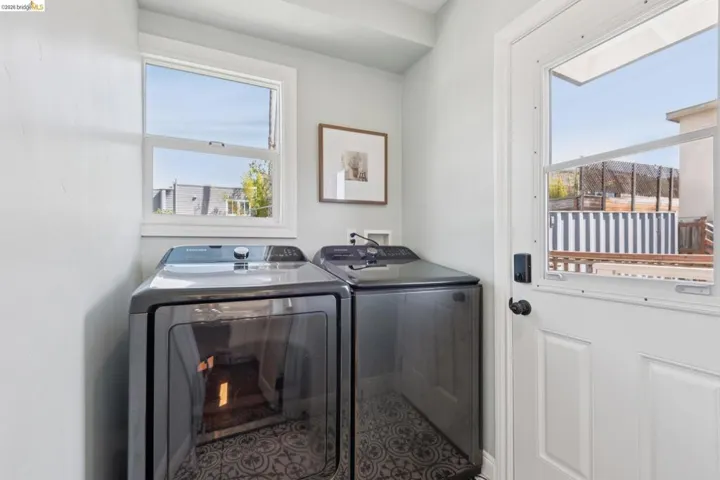 Laundry area featuring a window, patterned floor tile, and a door with a windowpane