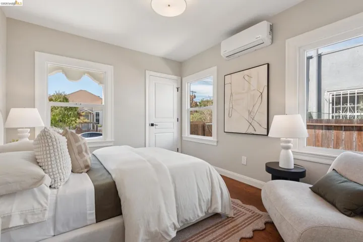 Hardwood flooring, white trim windows, neutral wall tones, white interior door, ceiling-mounted light fixture