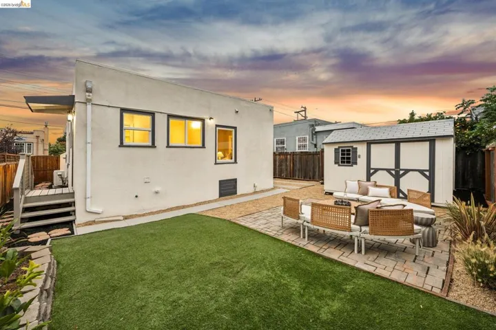 Expansive yard featuring artificial turf, a paver patio, gravel landscaping, and a detached storage shed