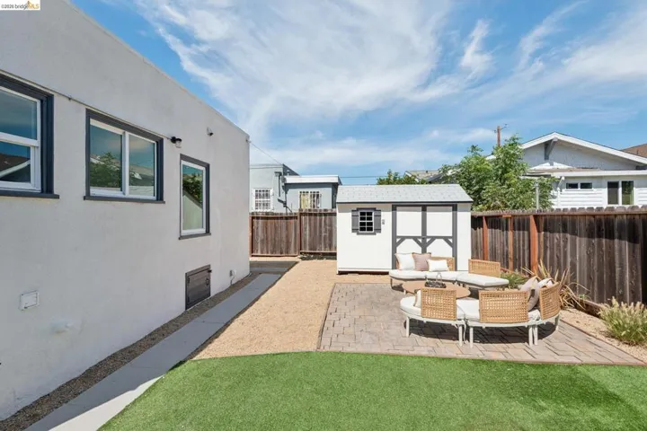 Manicured lawn with a brick paver patio, gravel hardscaping, and a backyard shed with shingled roof
