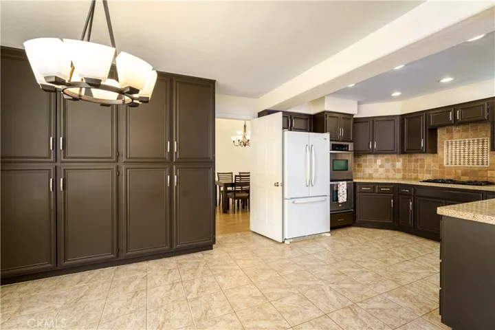 Warm brown painted cabinets with a casual tumbled travertine backsplash and granite or Quartz counter tops. Double stainless steel oven.