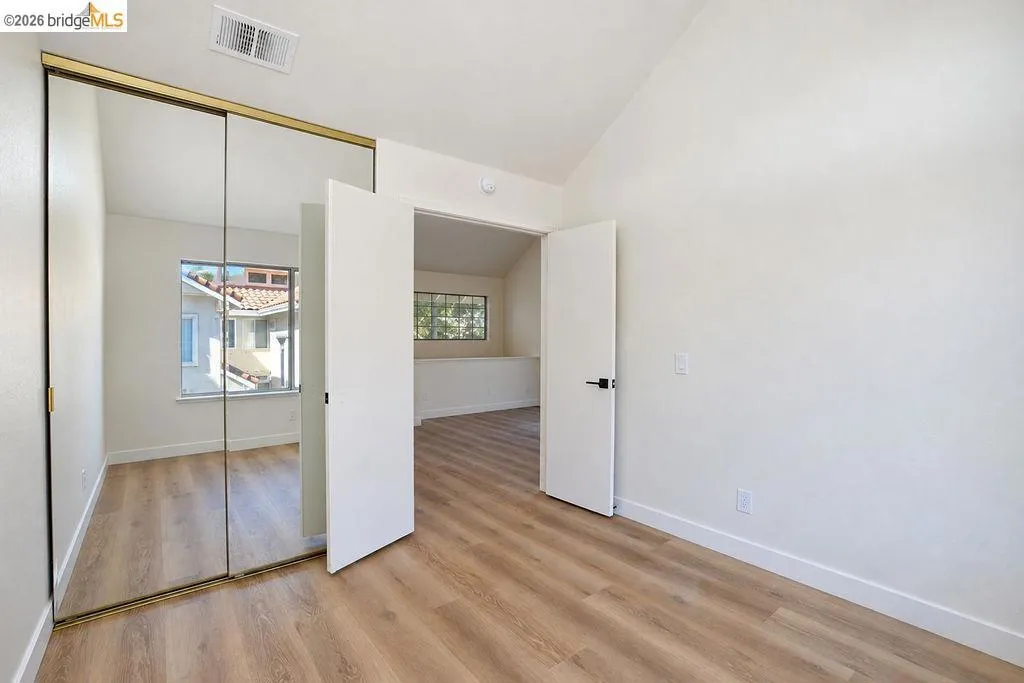 Wood-finish flooring throughout, mirrored closet doors, and modern interior doors with dark hardware