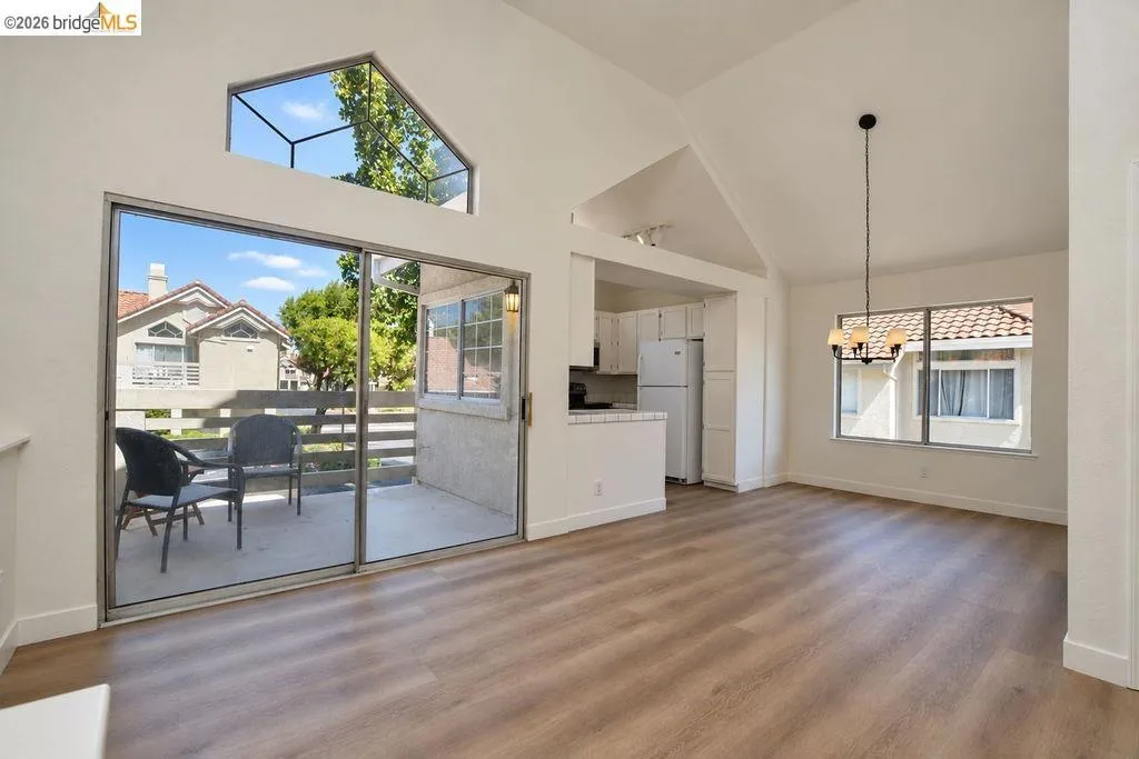 Vaulted ceilings, wood-finish flooring, and expansive sliding glass doors leading to a private patio