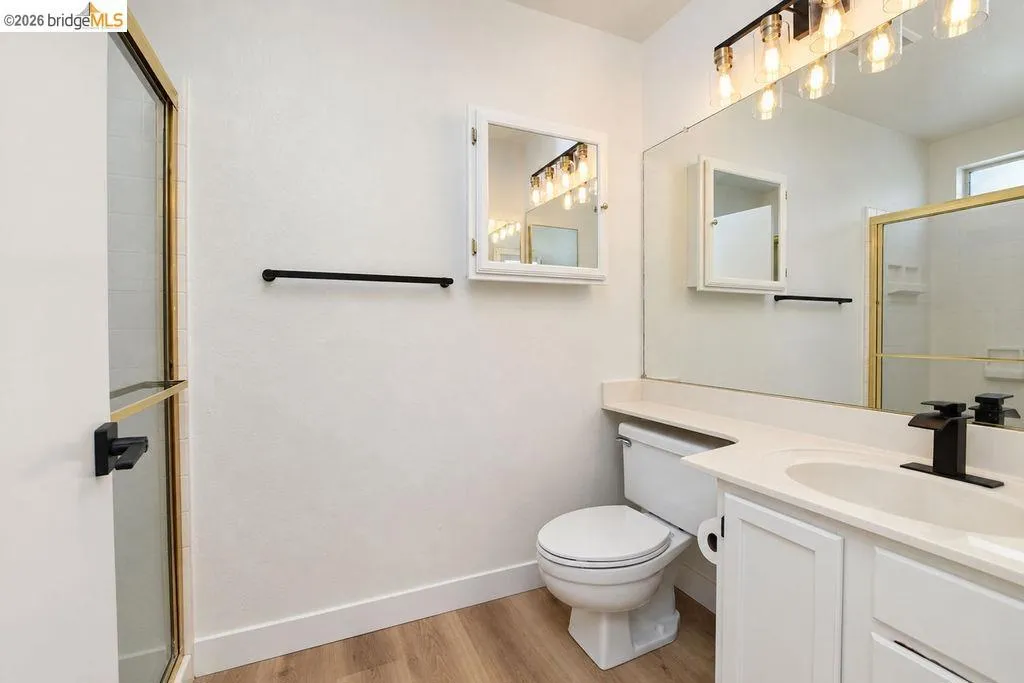 Bathroom featuring a single vanity with white cabinetry, light-toned countertop, and a black faucet