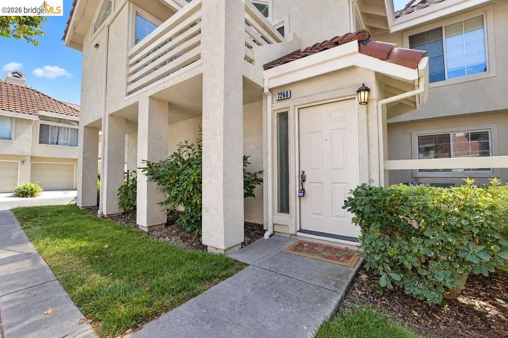 Entryway with a paneled door, exterior light fixture, and an overhead tile awning
