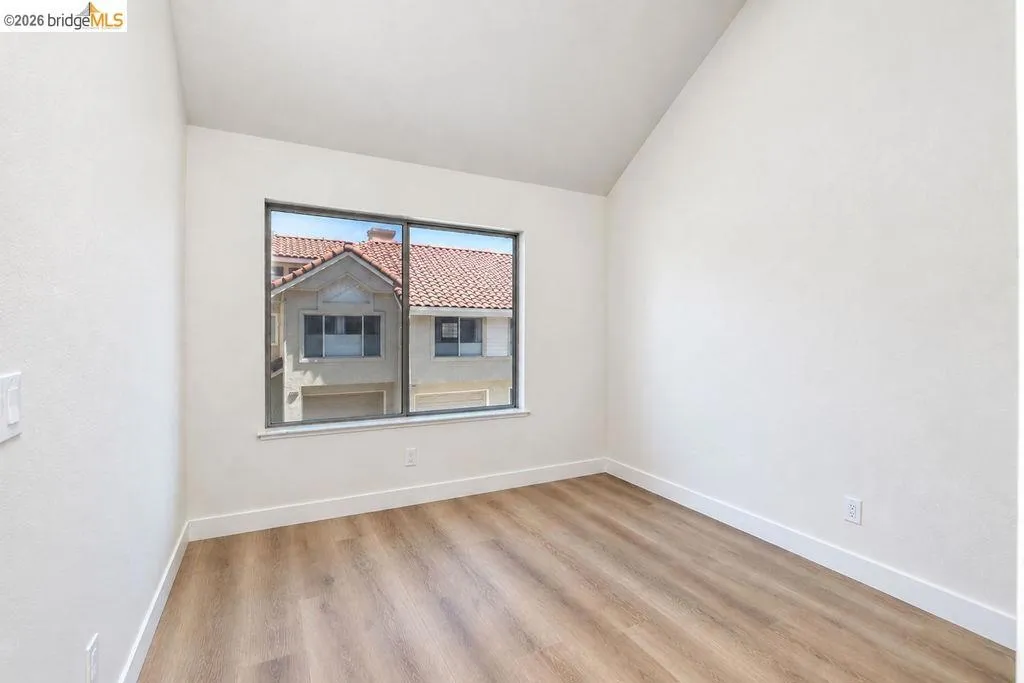 Wood-finish flooring, white walls, and a large window with white trim