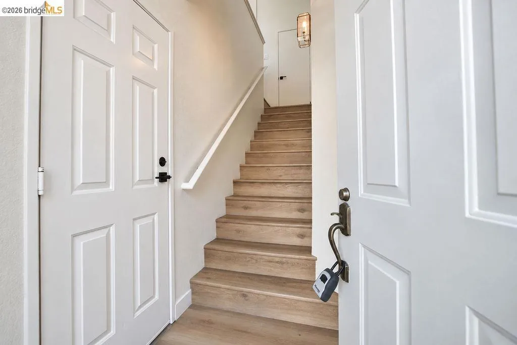 Wood-finish stairs with a white handrail, framed by two panel doors