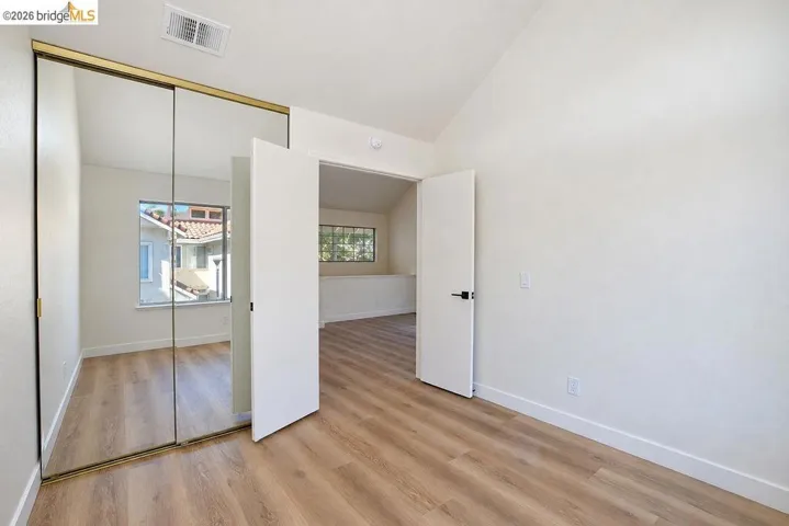 Wood-finish flooring throughout, mirrored closet doors, and modern interior doors with dark hardware