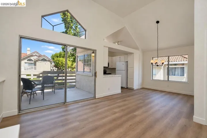 Vaulted ceilings, wood-finish flooring, and expansive sliding glass doors leading to a private patio