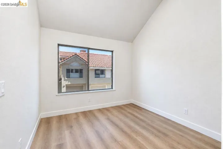 Wood-finish flooring, white walls, and a large window with white trim