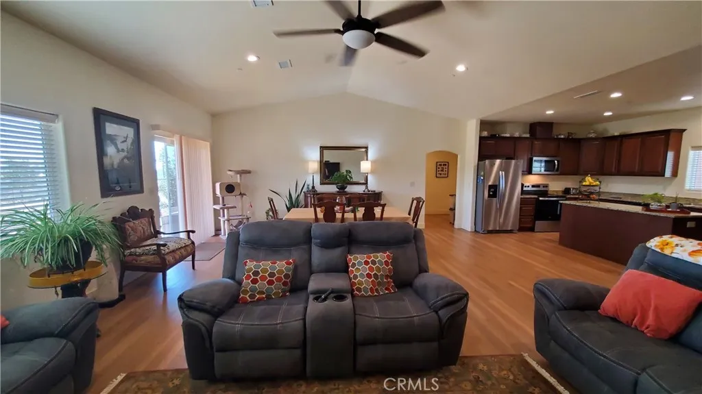 View of open living room area with vaulted ceilings, sliding glass door leading to covered patio on the left and kitchen with large island on the right. View of open living room area with vaulted ceilings, sliding glass door leading to covered patio on the left and kitchen with large island on the right.