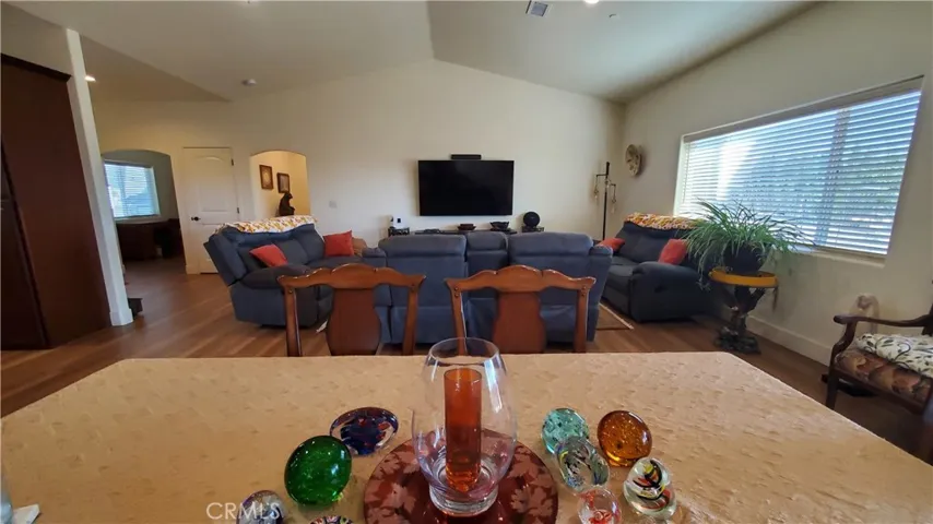 View from dining area overlooking living room with vaulted ceilings and large window with view into the back yard.
