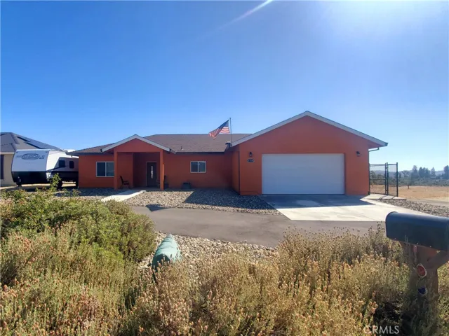 View of 1724 Ellis Drive from road, RV parking area on the left and side access gate to fenced back yard on the right.