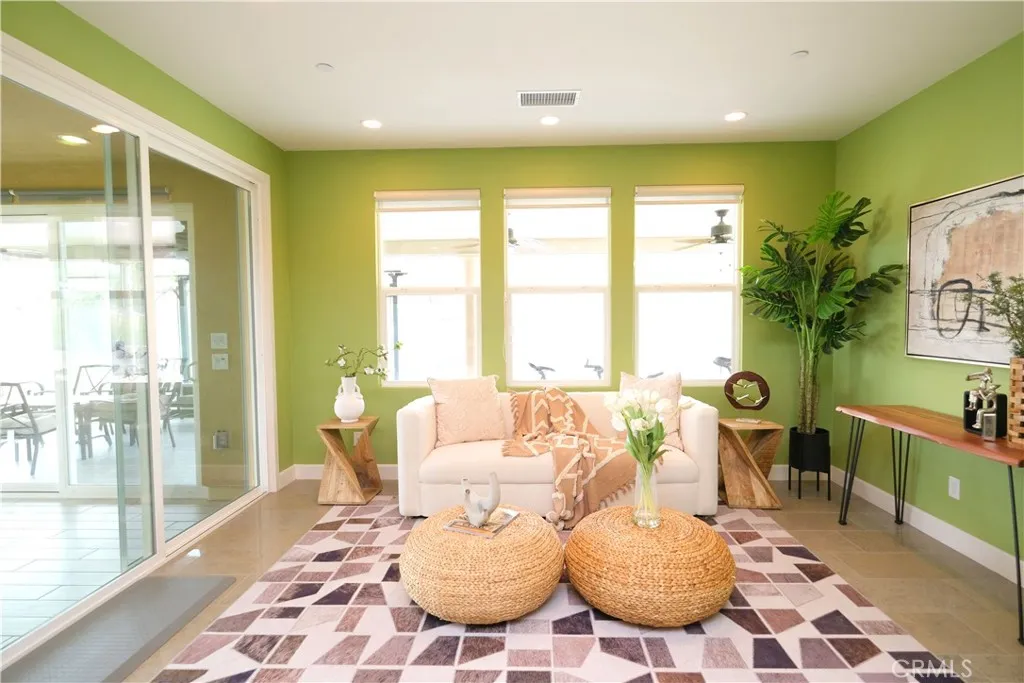 Cheerful sitting area with green accent walls, abundant natural light, and sliding glass doors. Cheerful sitting area with green accent walls, abundant natural light, and sliding glass doors.