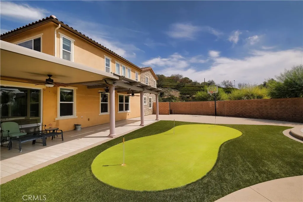 Backyard putting green bordered by a paved patio and the home's rear exterior. Backyard putting green bordered by a paved patio and the home's rear exterior.