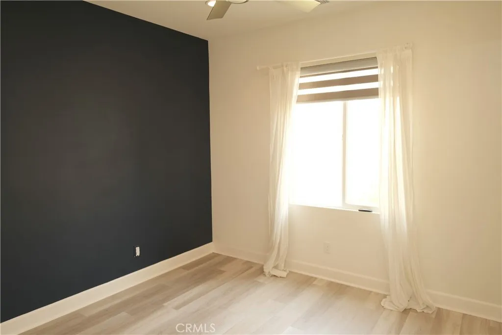 Bedroom featuring a dramatic dark accent wall and a window that welcomes natural light. Bedroom featuring a dramatic dark accent wall and a window that welcomes natural light.