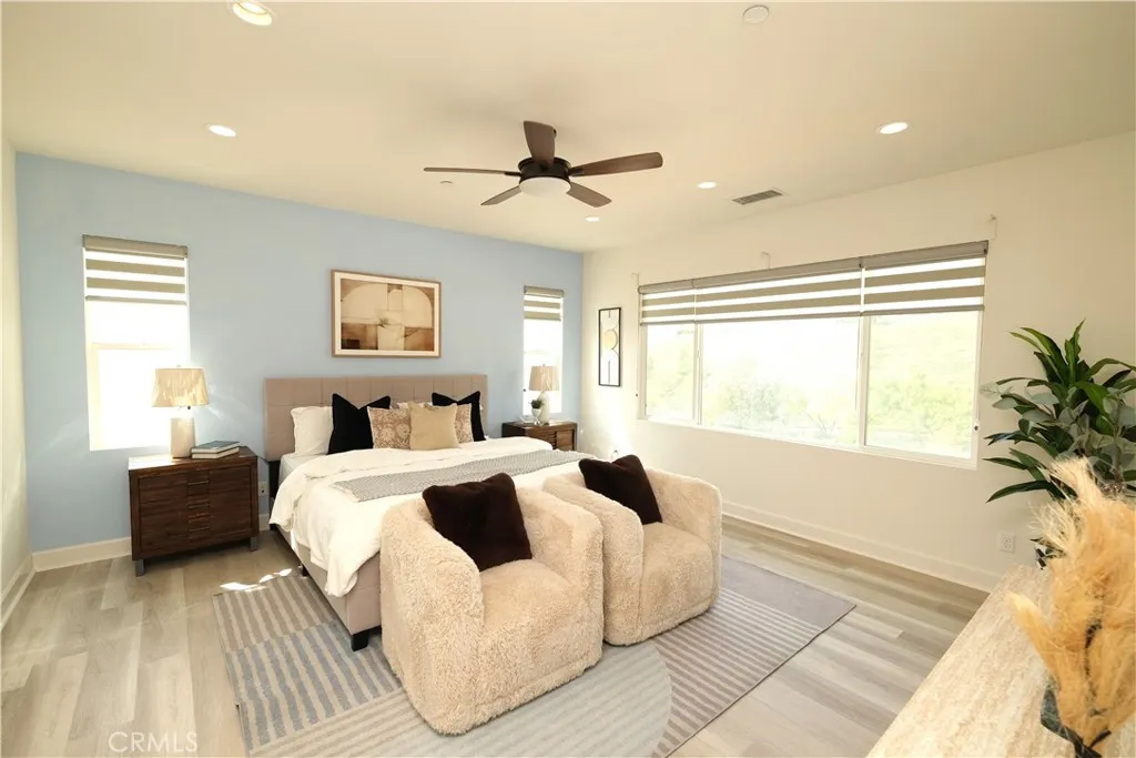 Spacious bedroom retreat featuring broad windows, an accent wall, and a ceiling fan. Spacious bedroom retreat featuring broad windows, an accent wall, and a ceiling fan.