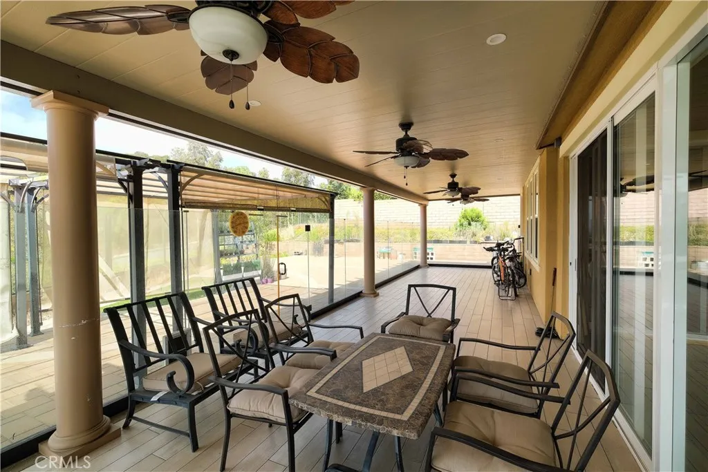 Sheltered patio seating area with ceiling fans and views toward the backyard. Sheltered patio seating area with ceiling fans and views toward the backyard.