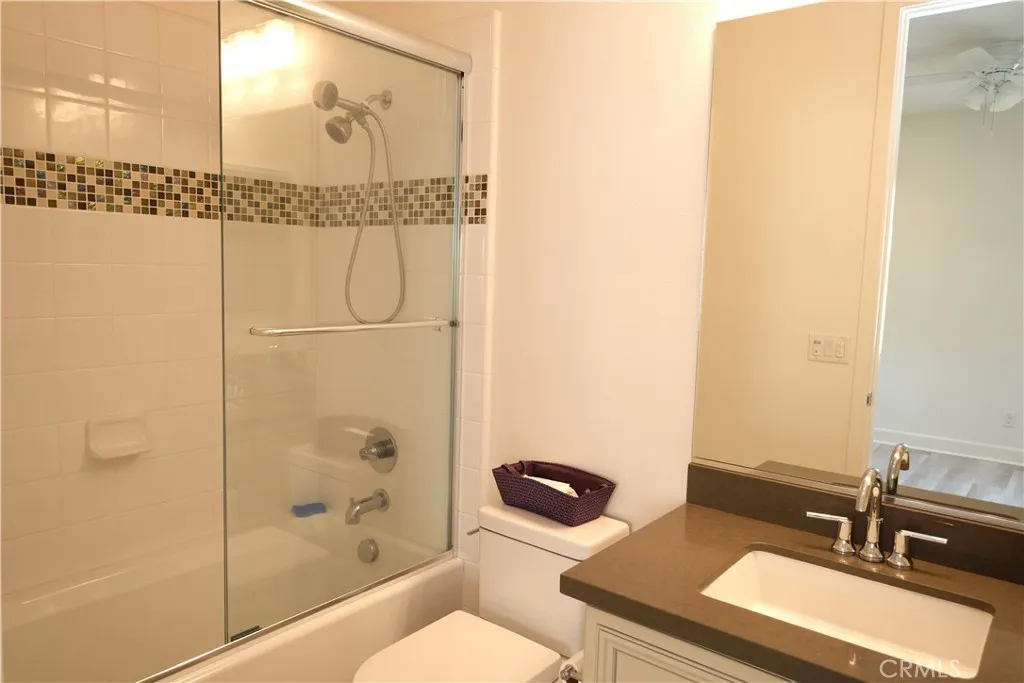 Bathroom with a glass-enclosed shower, decorative tile accents and a vanity. Bathroom with a glass-enclosed shower, decorative tile accents and a vanity.