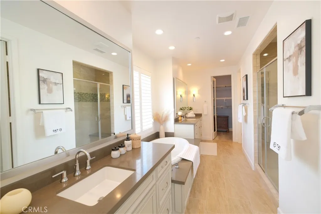 Spacious bathroom featuring separate vanity areas, large mirrors, and extensive cabinetry. Spacious bathroom featuring separate vanity areas, large mirrors, and extensive cabinetry.