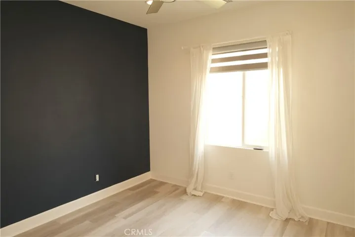 Bedroom featuring a dramatic dark accent wall and a window that welcomes natural light.