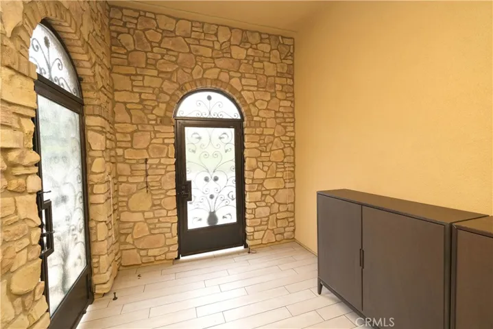 arched glass entry framed by textured stone accents and warm architectural details.