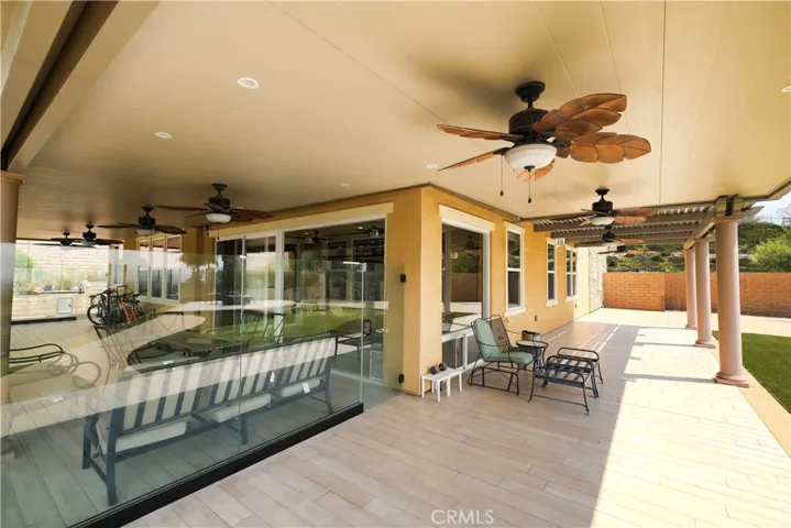 Spacious covered patio with seating areas and ceiling fans for comfortable outdoor gatherings.
