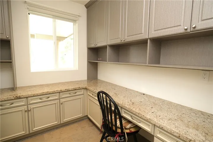 Built-in workspace featuring a long desktop, overhead cabinetry, and natural light.