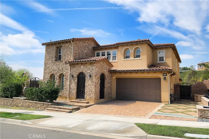 Closwer exterior view highlighting the arched doorway, textured architectural accents, and attached garage.