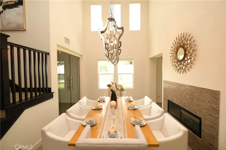 Invinting dinning space illuminated by decorative chandeliers and tall windows.