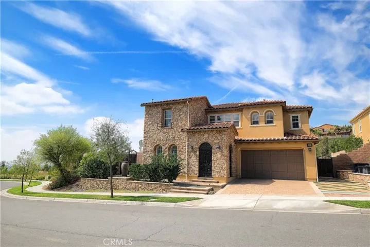 Inviting curb appeal with warm stucco finishes, tiled rooflines, and a paved driveway.