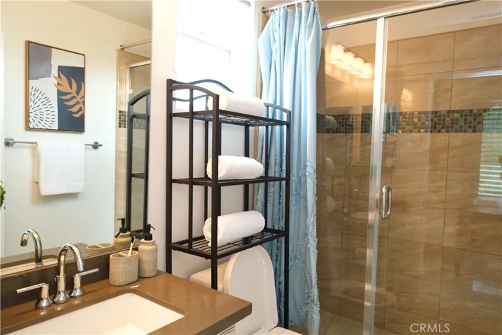 Bathroom featuring a vanity and a glassenclosed shower with decorative tile accents.